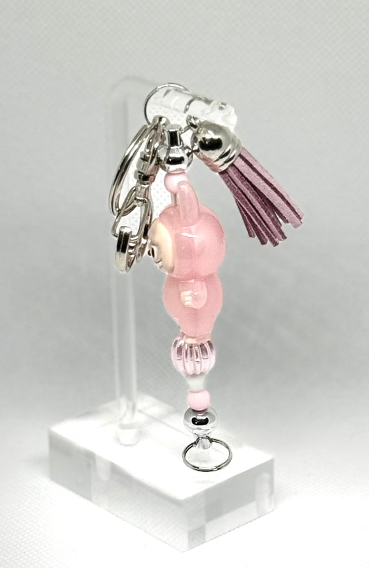 Side view of a Handmade silver key chain inspired by the Labubu character. Featuring leather tassel and pink Labubu character charm. Perfect
For Labubu fans and collectors.