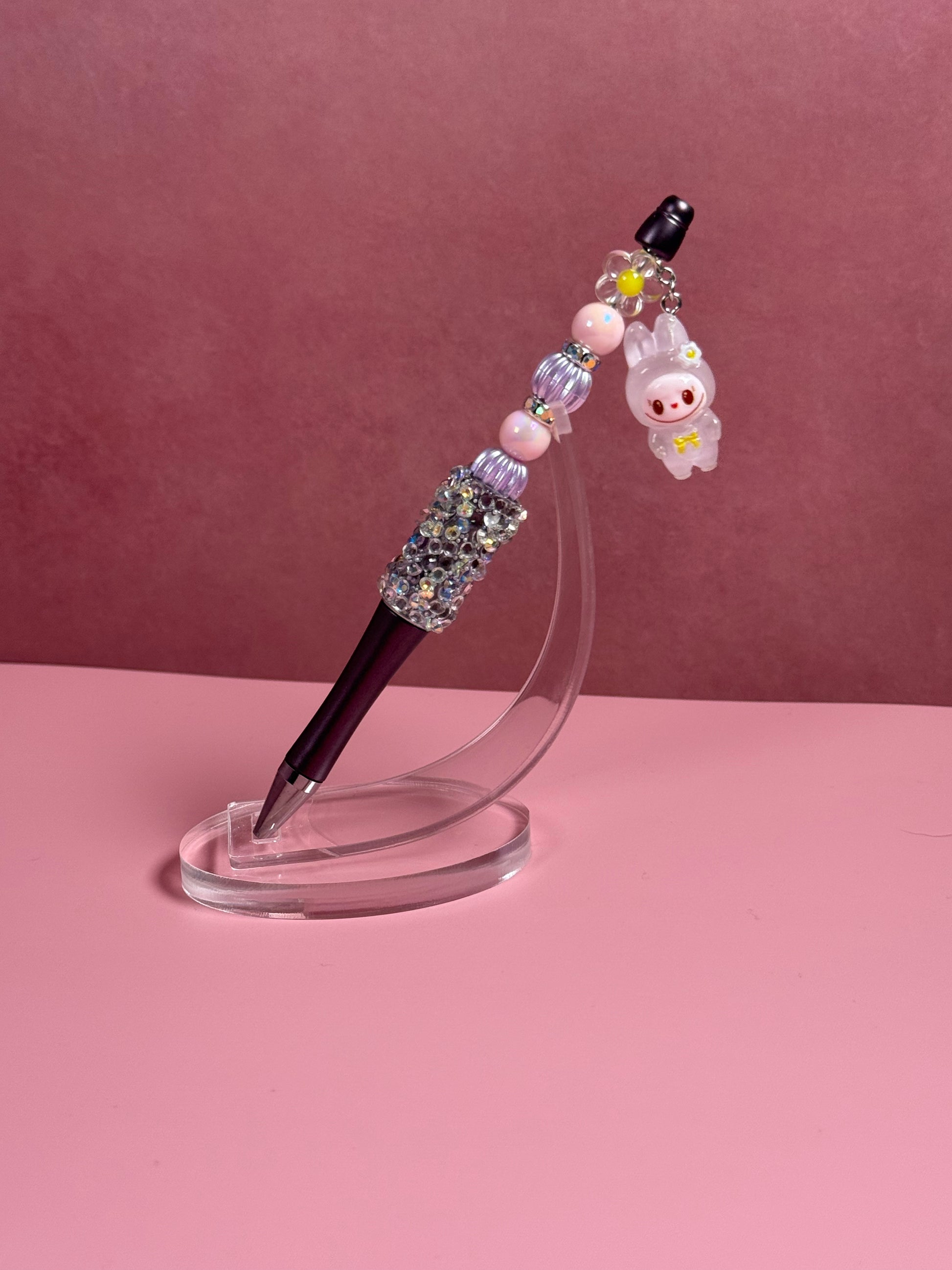 Handmade beaded pen inspired by the Labubu Character, featuring pink and light purple beads and a pink 
Labubu character charm